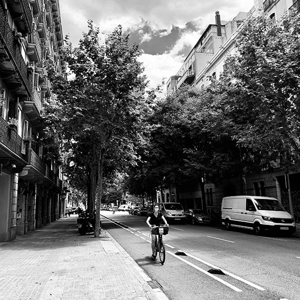 bicyclist in mask riding down Barcelona street daytime